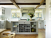 Roller blinds at windows in timber-framed kitchen with fitted wine rack in West Sussex farmhouse kitchen, England, UK