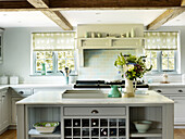 Cut flowers on kitchen island with tiled splashback in West Sussex farmhouse, England, UK