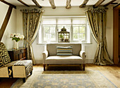 Embroidered curtains with tie-back at window with sofa in timber-framed West Sussex farmhouse, England, UK