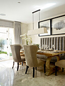 Upholstered chairs with pendant light above dining table in London townhouse, UK