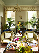 Pair of gold armchairs with houseplants in London townhouse apartment, UK