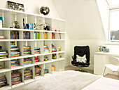 :large shelving unit and black chair with Union Jack cushion in London bedroom, UK