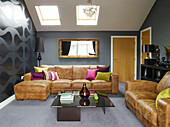 Brown leather sofas with lit framed mirror in attic conversion of Manchester home, England, UK