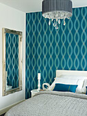Blue patterned wallpaper with full length silver framed mirror in bedroom of Manchester home, England, UK