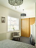 Wooden sliding doors with buttoned armchair at window in Manchester bedroom, England, UK