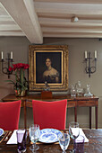 Red velvet dining chairs and artwork with table in timber framed Kent cottage, England, UK