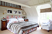 Fur throw on floral patterned bed in timber framed Kent cottage, England, UK