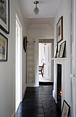 Black and white hallway with lit fire and ladder for access to ceiling hatch in London home UK