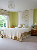 Double bed with co-ordinated leaf patterned blinds cushion and head panel in Cambridgeshire home UK