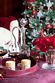 Red wine and lit candles with cur flowers at Christmas in Kent home, England, UK
