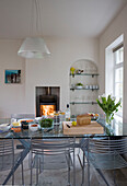 Tisch mit Glasplatte und Holzofen im Esszimmer eines Hauses in Sussex UK