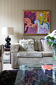 Ostrich feather cushions on beige sofa below modern art