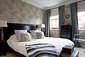 Striped blanket on double bed in room with patterned wallpaper