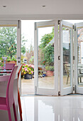 Pink dining chairs and view through concertina door to garden of Wepham home Sussex UK