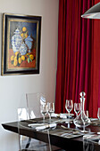 Glassware and artwork with red curtains in dining room of Newmarket home Suffolk UK