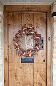 Weihnachtskranz an Holztür eines Hauses in den Cotswolds UK