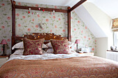 Floral cushions on bed of Cotswolds home UK