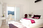 White bedroom with pink soft furnishings and view through sliding door to Mediterranean sea, holiday villa, Republic of Turkey