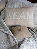 Cushion with the word 'Dream' on light blue quilt London UK