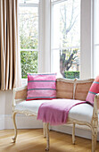 Pink cushions on wicker sofa London UK