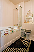 Cremefarben getäfeltes Badezimmer mit schwarzem Toilettensitz und Teppich London UK
