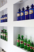 Blue and green medicine bottles on shelving in contemporary London townhouse, UK