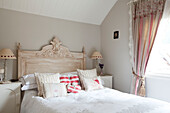Geschnitztes Holzkopfteil im Schlafzimmer mit passenden Lampen in einem Haus in Sussex, Großbritannien