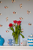 Vase of tulips on shelf with dog patterned wallpaper