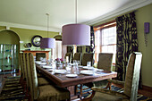 Place settings on wood table with oversized lilac lampshades in Suffolk home UK