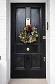 Black front door with Christmas garland London UK