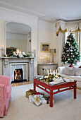 Beleuchtete Kerzen und Weihnachtsbaum und Geschenke im Wohnzimmer eines Londoner Hauses, UK