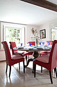 Red leather dining chairs at table in Sussex farmhouse, UK