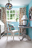 Floral cushion on chair with desk and laptop at window of Sussex farmhouse, UK