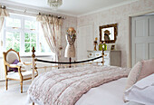 Pink wuilt with gilded armchair and mirror in master bedroom of classic Berkshire home, England, UK