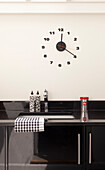 Wall mounted clock above black kitchen counter in contemporary London home, UK