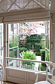 View through open double windows to courtyard garden of contemporary London townhouse, England, UK