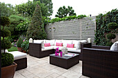 Outdoor seating with topiary on terrace in London garden, UK