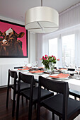 Dining room table with large picture of cow in harness, contemporary home, Hove, East Sussex, England, UK