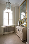 Arched window above radiator cover in London townhouse with gilt mirror