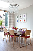 Dining table an chairs under glass chandelier in contemporary London townhouse, England, UK