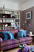 Blue cushions on sofa with bookcase in living room of contemporary London townhouse, England, UK