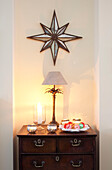 Star shaped wall decoration above antique wooden chest of drawers in London home, UK