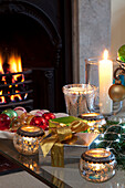 Christmas decorations with lit candle by fireside in London home, UK