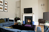 Wall mounted plasma screen above lit fire in living room of classic London home, UK