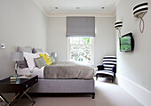 Wall mounted plasma screen in grey bedroom with black and white co-ordinated furnishings in classic London home, UK