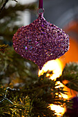 Purple jewelled Christmas bauble hangs from Christmas tree in London home, UK