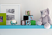Building blocks with soft to y and silver piggy bank on shelf in child's nursery of contemporary London home, UK
