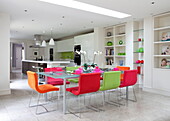 Multicoloured dining chairs at table in open plan contemporary London home, England, UK