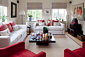 Contrasting red and white living room with orchid and candles on table in London home, England, UK
