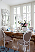 Wooden dining room table detail with white ornate mirror in contemporary London home, UK
